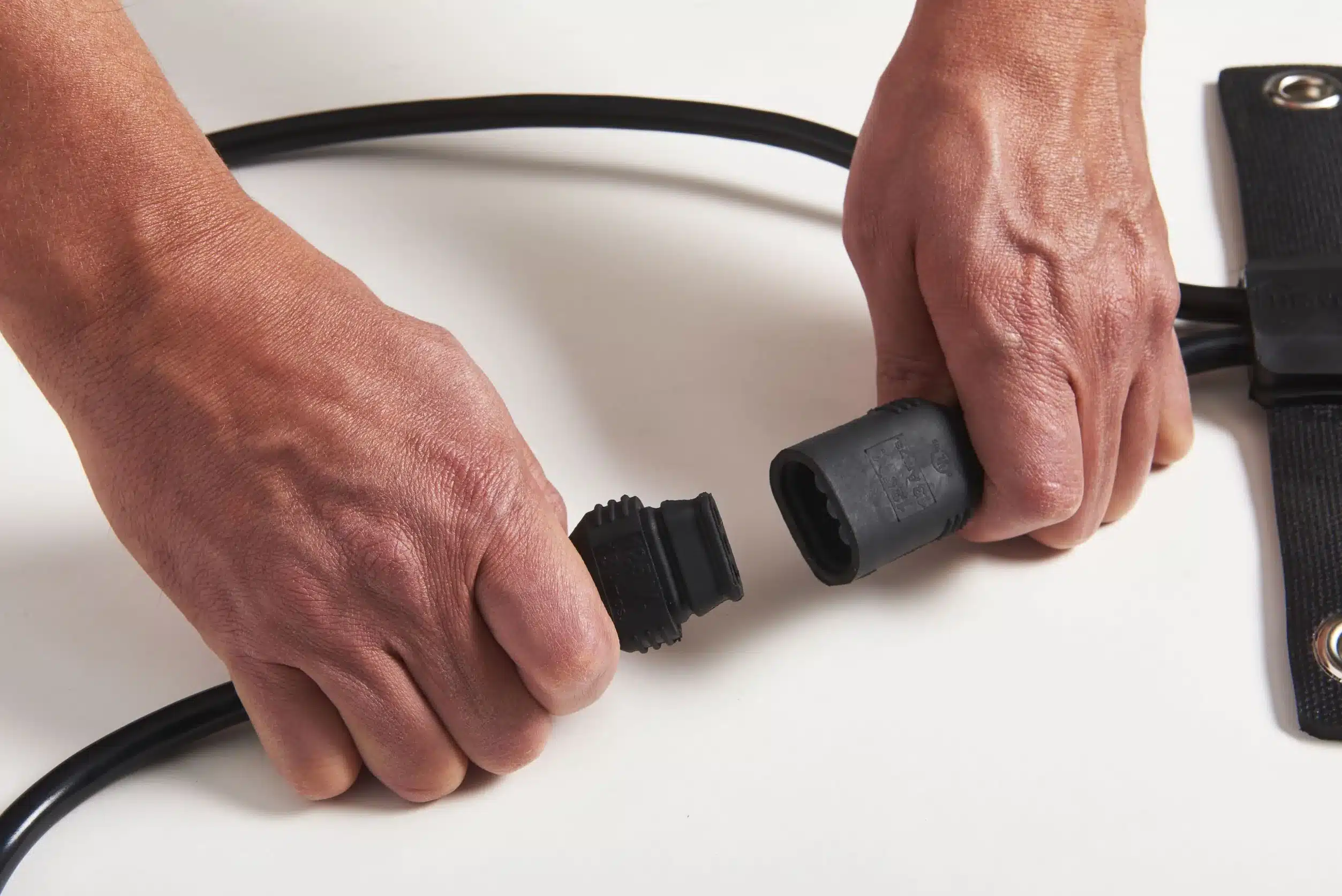Hands aligning a HeatTrak Watertight Cable Extender connector with a heated mat connector